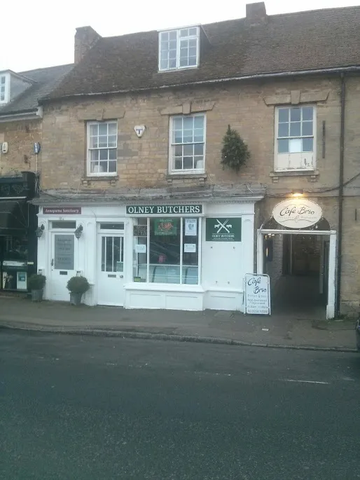 The stone building on Olney Market Place, with the white Olney Butchers shopfront and green fascia on the ground floor